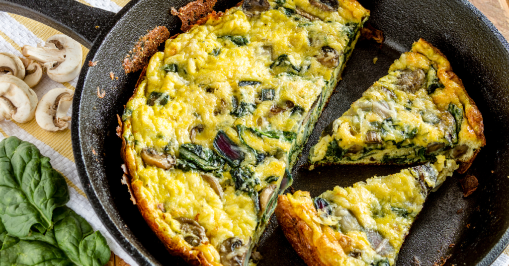 A Mediterranean quiche cooked in a pan, filled with spinach, feta cheese, and olives.